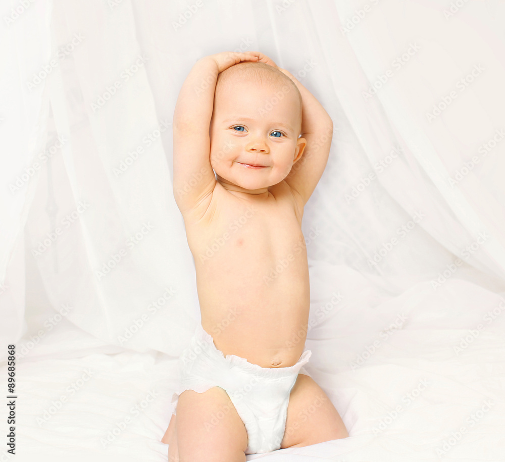 Portrait of active baby in diapers playing on the bed at home Portrait of active baby in diapers playing on the bed at home