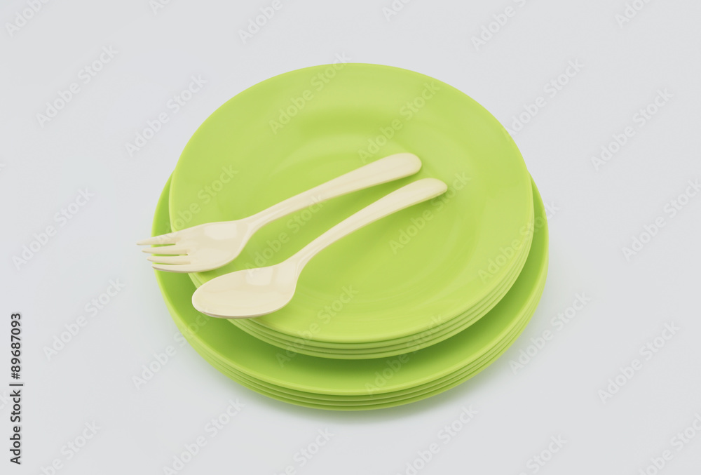 Stack of green plastic plate and dish with spoon isolated on whi Stack of green plastic plate and dish with spoon isolated on whi