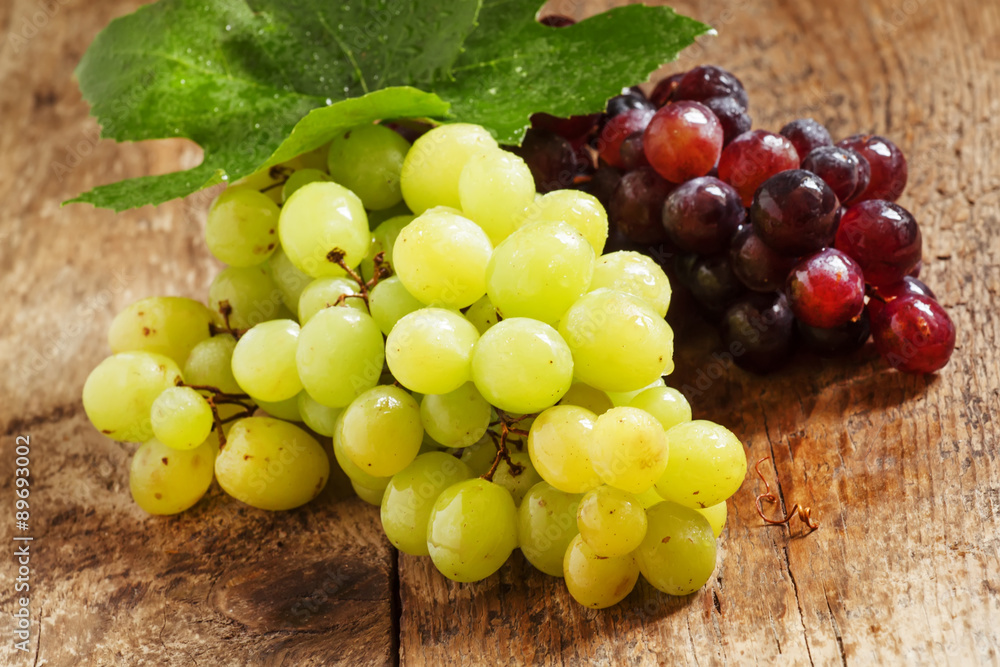 Green and purple round grapes on old wooden table, selective f Green and purple round grapes on old wooden table, selective f