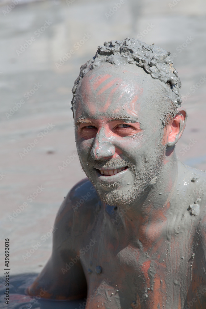 Man in grey mud bath. Dalyan, Turkey