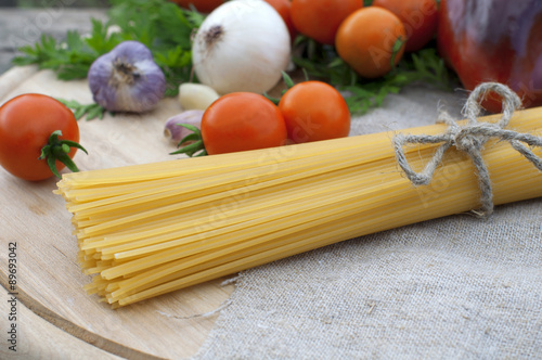 Pasta spaghetti, onion, garlic and tomato on wooden background