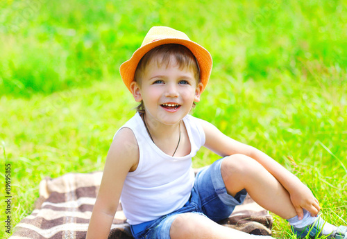 Portrait little boy child in hat sitting on the grass in summer © rohappy