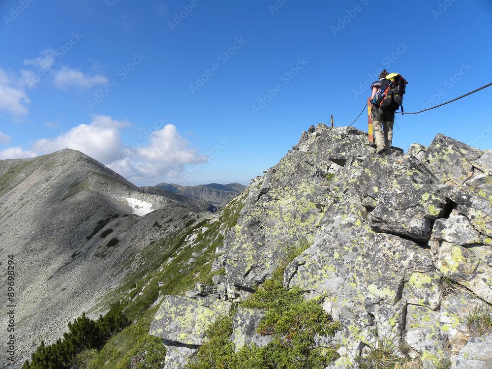 Young girl climbing by the rope on narrow mountain ridge