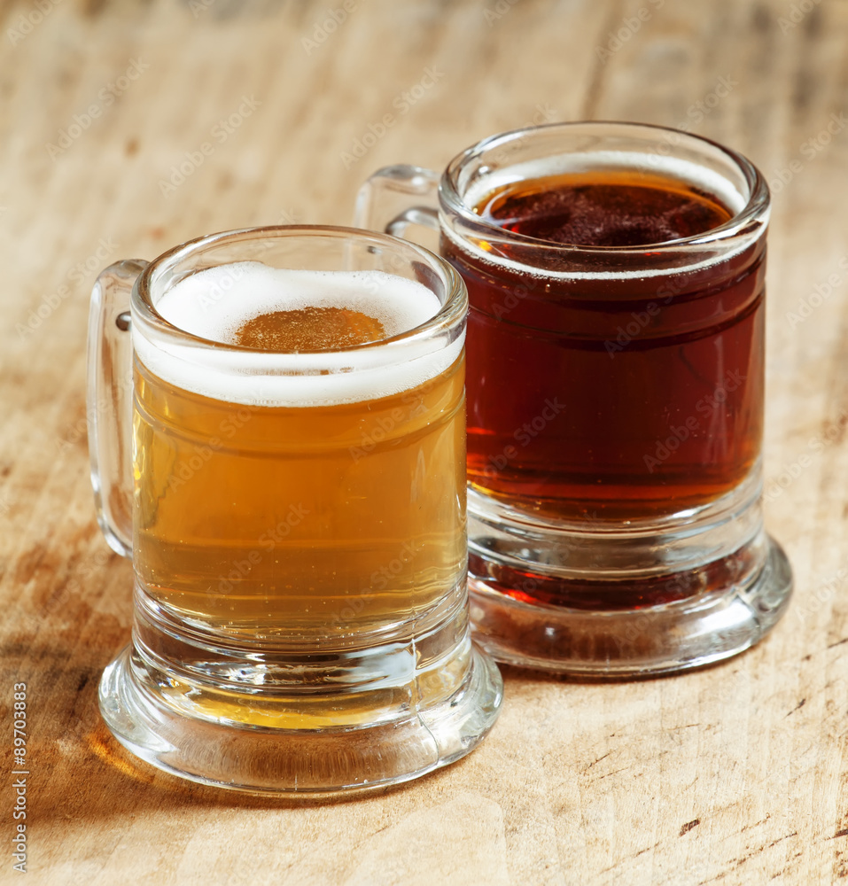 Light and dark beer in old-fashioned circles on old wooden table Light and dark beer in old-fashioned circles on old wooden table