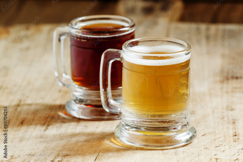 Light and dark beer in old-fashioned circles on old wooden table Light and dark beer in old-fashioned circles on old wooden table