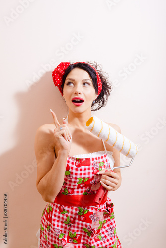 Young beautiful amazed woman holding paint roller 