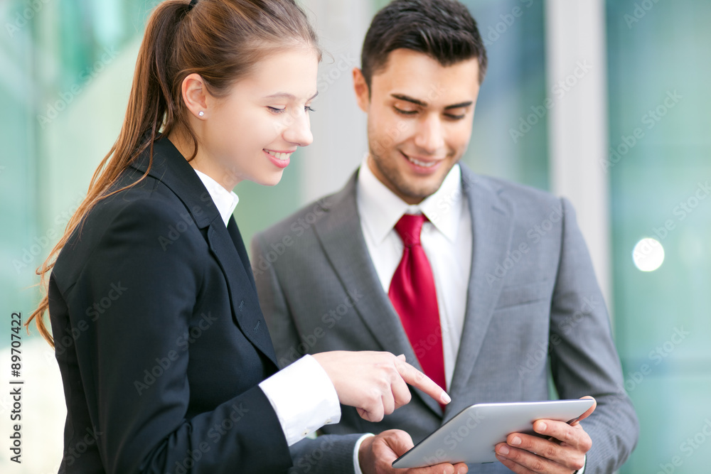 Two business people using a tablet in an urban setting Two business people using a tablet in an urban setting