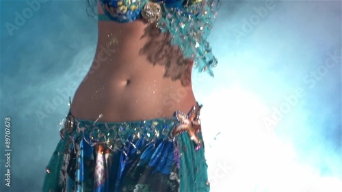 Middle section of a woman's body dancing belly dance, in smoke