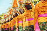 Procession of beautiful Balinese women in traditional costumes - sarong, carry offering on heads for Hindu ceremony. Arts festival, culture of Bali island and Indonesia people, Asian travel background