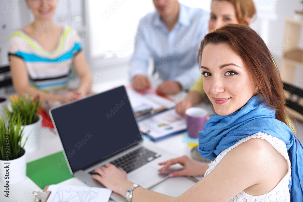 Portrait of attractive female designer sitting on desk in Portrait of attractive female designer sitting on desk in