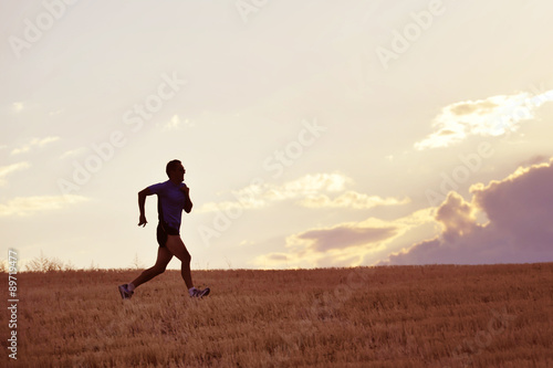 profile silhouette of young man running in countryside training in summer sunset
