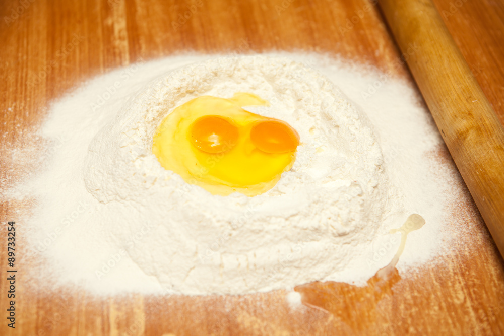raw eggs in the flour on a wooden table raw eggs in the flour on a wooden table