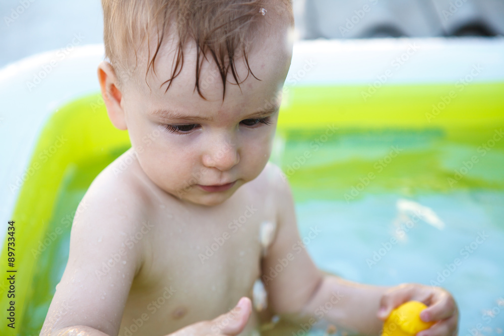 child bathes in inflatable pool outdoors, close-up portrait child bathes in inflatable pool outdoors, close-up portrait