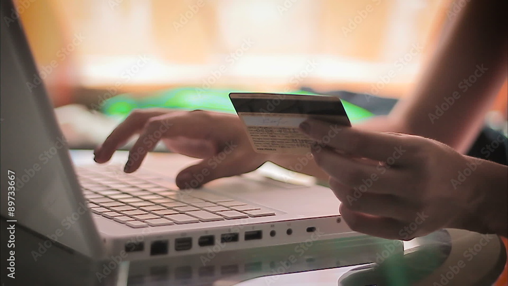 Woman entering information from a credit card using laptop Woman entering information from a credit card using laptop