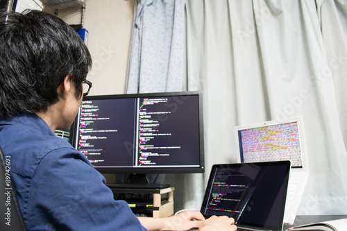 Plakat Asian engineer writing a programme on a computer