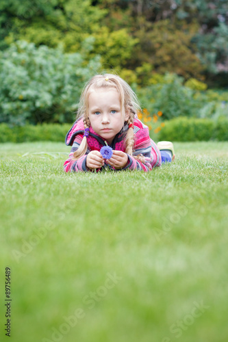 Ein Mädchen liegt auf dem Rasen