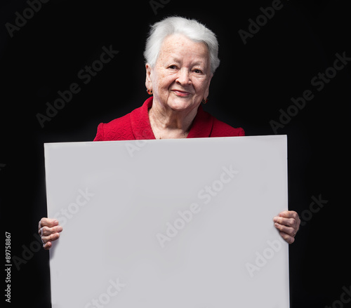 Portrait of happy old woman holding blank billboard