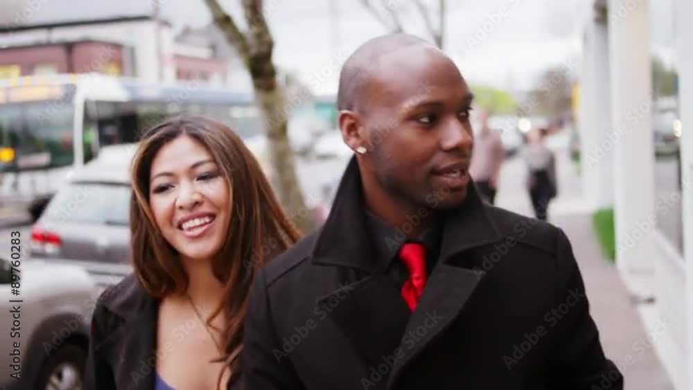 A couple walk down the street while holding hands A couple walk down the street while holding hands