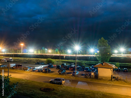 car parking at night with street lights and dark clouds