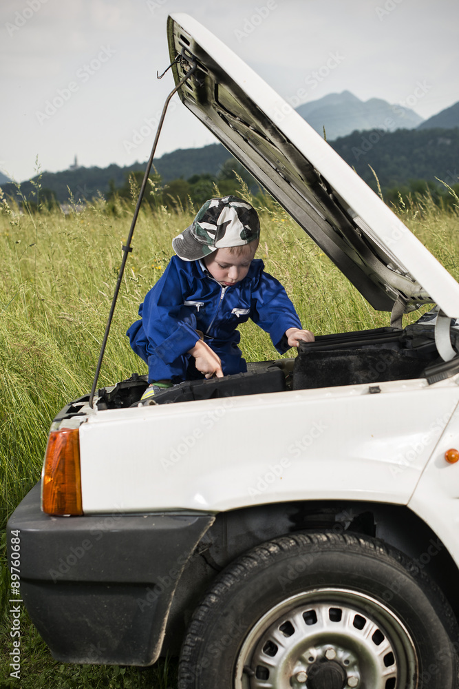 Bambino meccanico al lavoro su motore auto