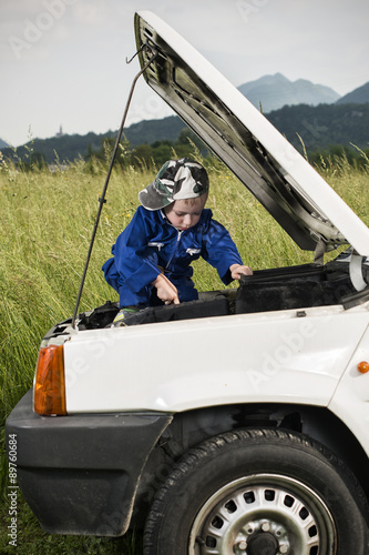 Obraz na płótnie Bambino meccanico al lavoro su motore auto w salonie
