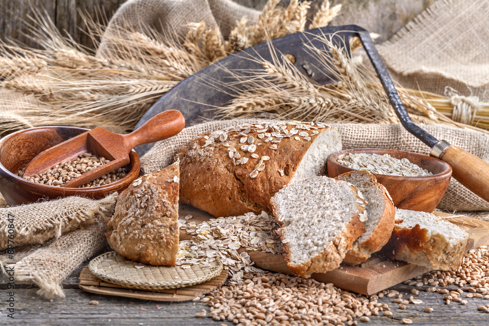 Bread from rye and healthy grains on an old rustic table with a sickle in the background Bread from rye and healthy grains on an old rustic table with a sickle in the background
