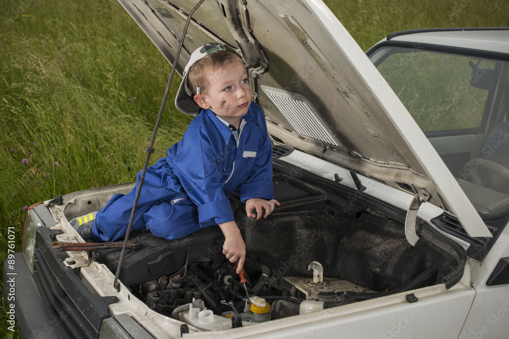 Bambino meccanico al lavoro su motore auto