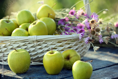 Green apples with bouquet of wildflowers on wooden table, closeup