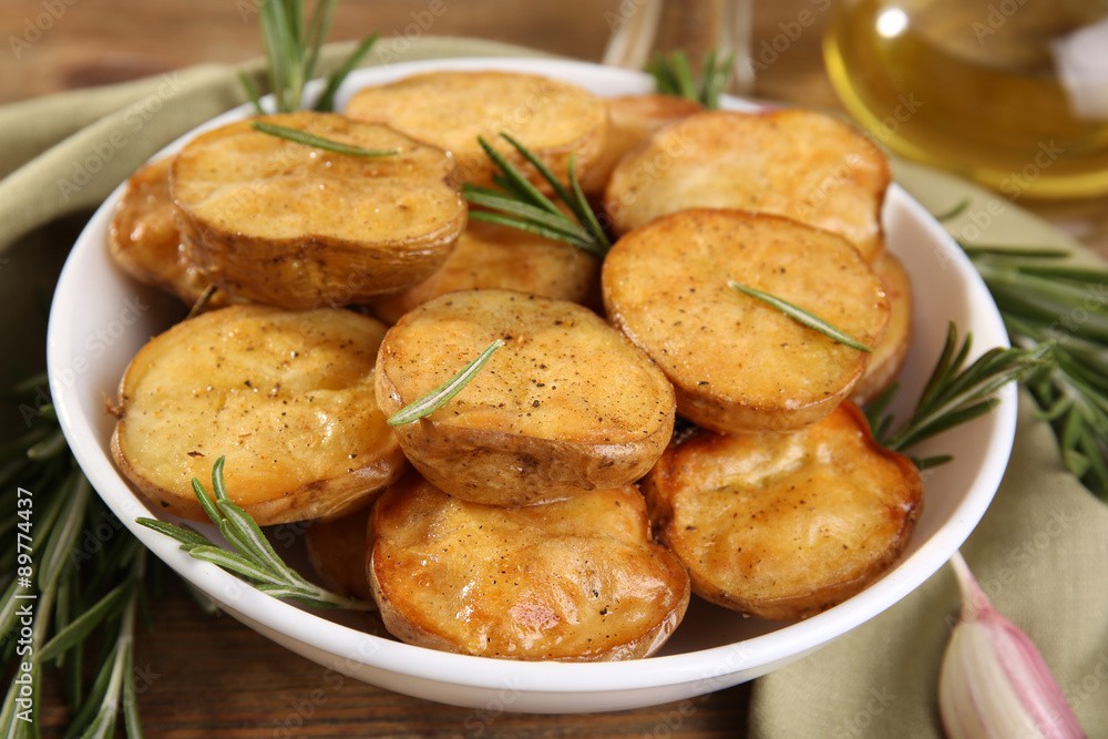 Delicious baked potato with rosemary in bowl on table close up Delicious baked potato with rosemary in bowl on table close up