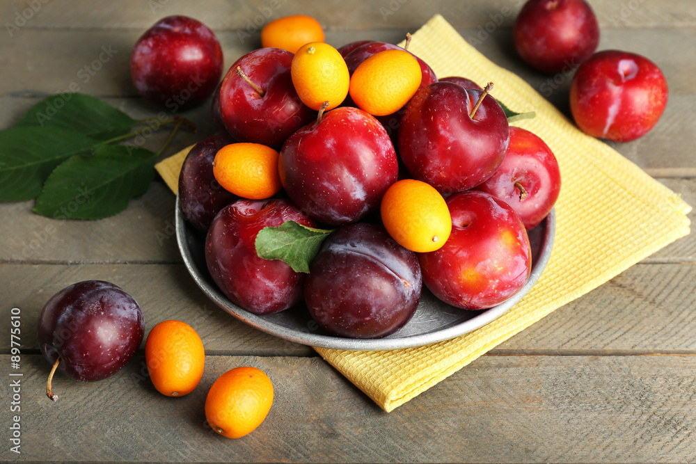 Ripe plums in metal plate on wooden background Ripe plums in metal plate on wooden background