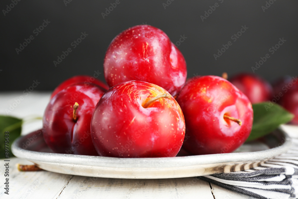 Ripe plums in metal plate on wooden table on dark background Ripe plums in metal plate on wooden table on dark background