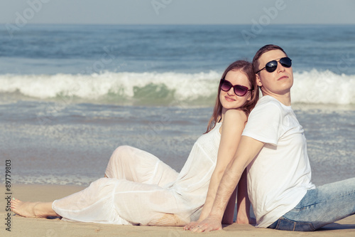 Loving couple sitting on the beach at the day time. © atakaa