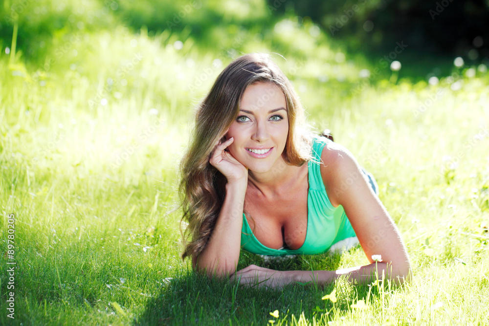 young woman in green dress lying on grass young woman in green dress lying on grass