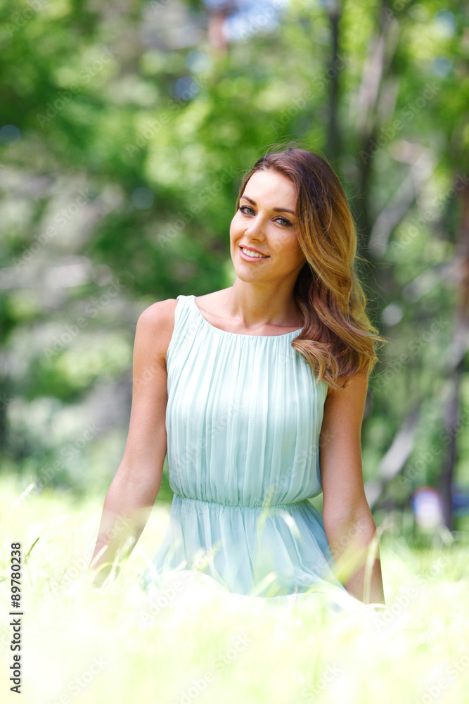 young woman in blue dress sitting on grass young woman in blue dress sitting on grass