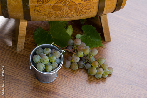 Белый виноград в маленьком ведре и бочка вина