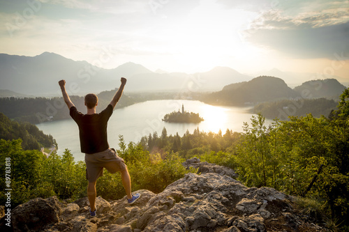 Man with hands up on top of the mountain
