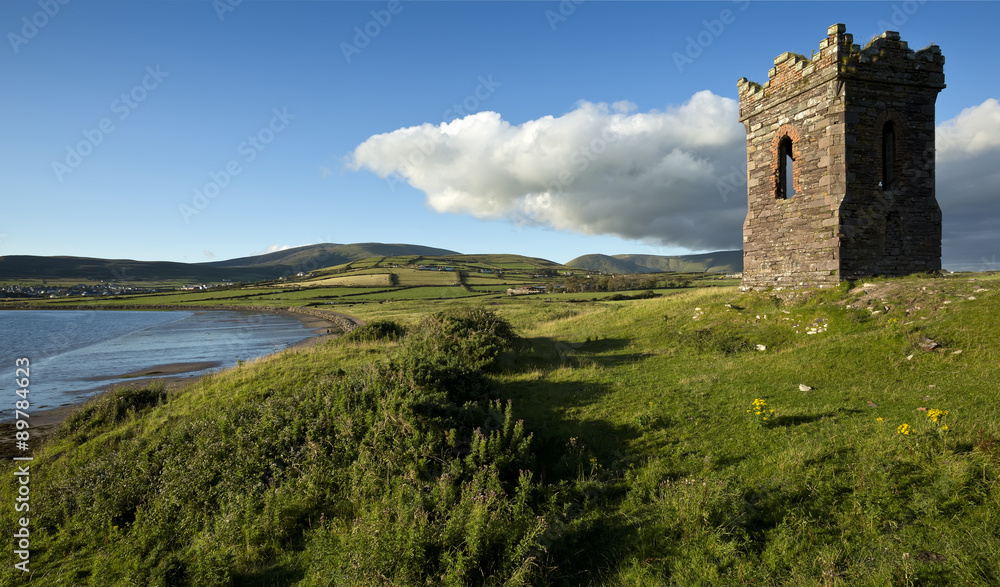 An old stone Watch tower over looking Dingle Bay Co. Kerry Ireland as a fishing boat heads out to sea. An old stone Watch tower over looking Dingle Bay Co. Kerry Ireland as a fishing boat heads out to sea.