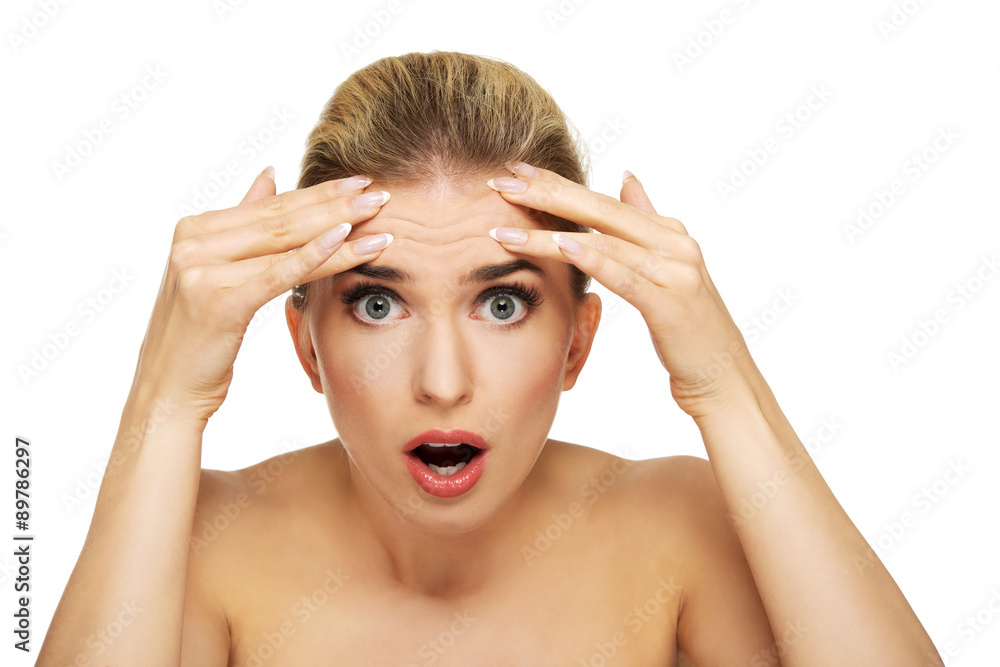 Young woman checking wrinkles on her forehead Young woman checking wrinkles on her forehead