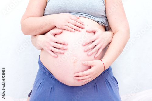 Parents hands on pregnant belly