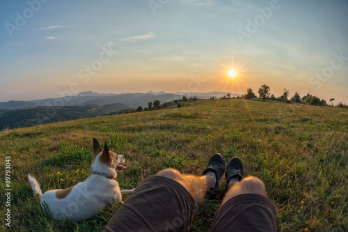 traveller and his dog sitting in the grass and watching the suns © catgrig