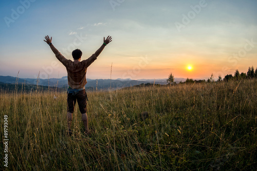 traveller raising his arms in the sunset