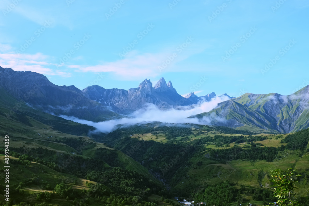 Overlooking floating clouds in the Arvan Valley with the Aiguilles d'Arves peak in the french Alps