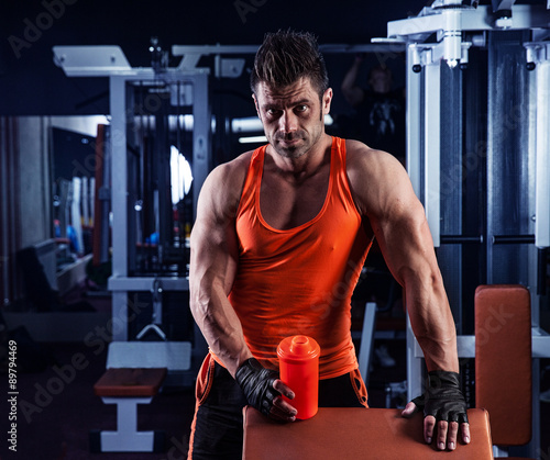 Obraz na płótnie handsome young muscular man drinks a protein in the gym