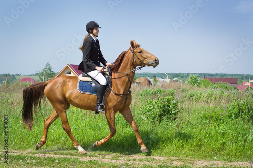 Beautiful girl jockey ridding horse in a field