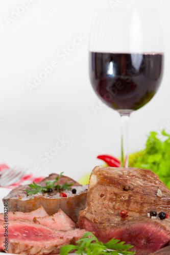 Beef steak on white plate with glass of red wine-vertical