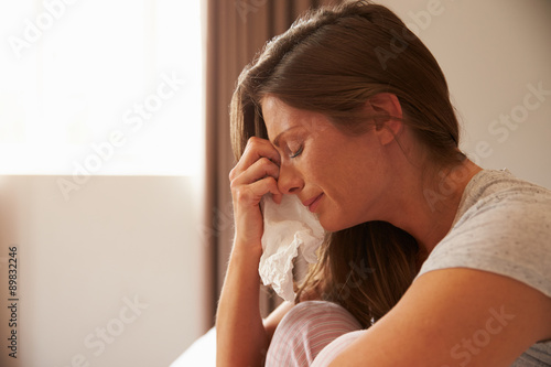 Valokuvatapetti Woman Suffering From Depression Sitting On Bed And Crying