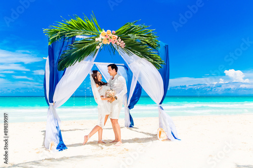 Wedding ceremony on a tropical beach in blue. Happy groom and br