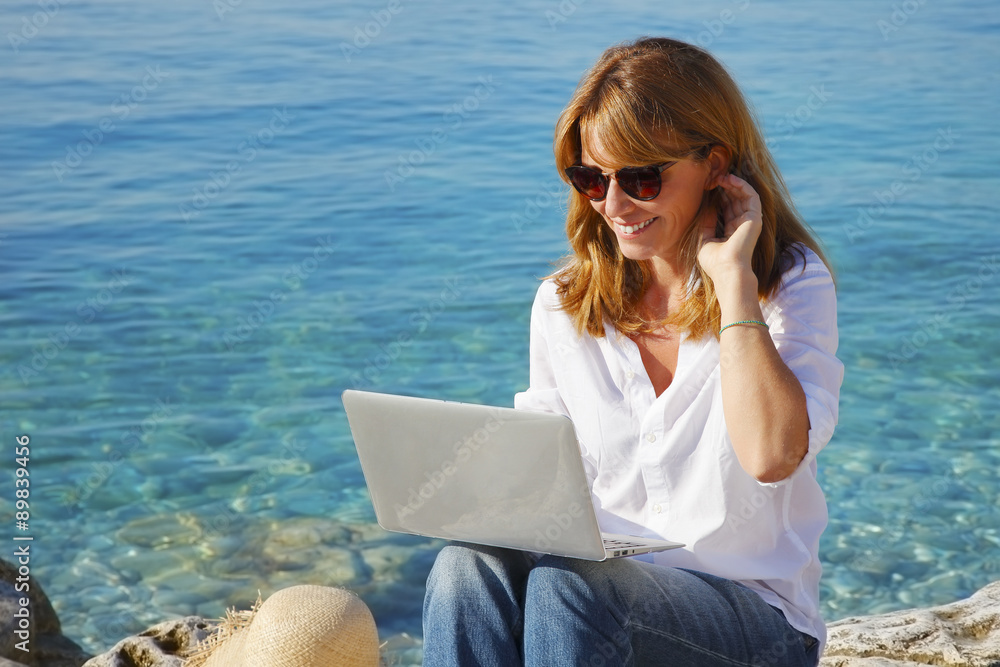 Woman by the sea with laptop