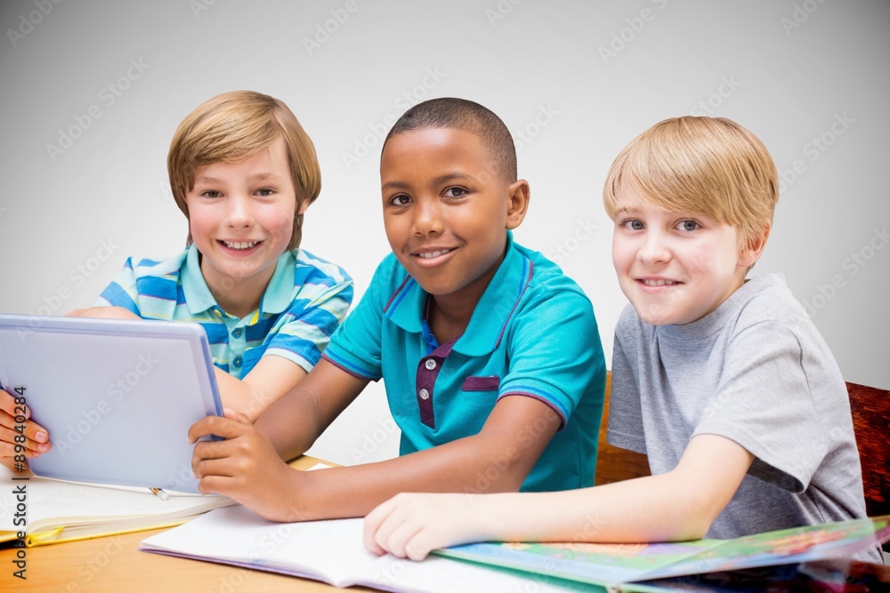 Composite image of cute pupils using tablet computer in library Composite image of cute pupils using tablet computer in library