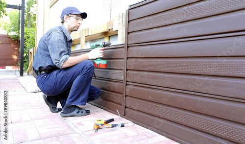 Worker installs plastic siding on the facade of the house